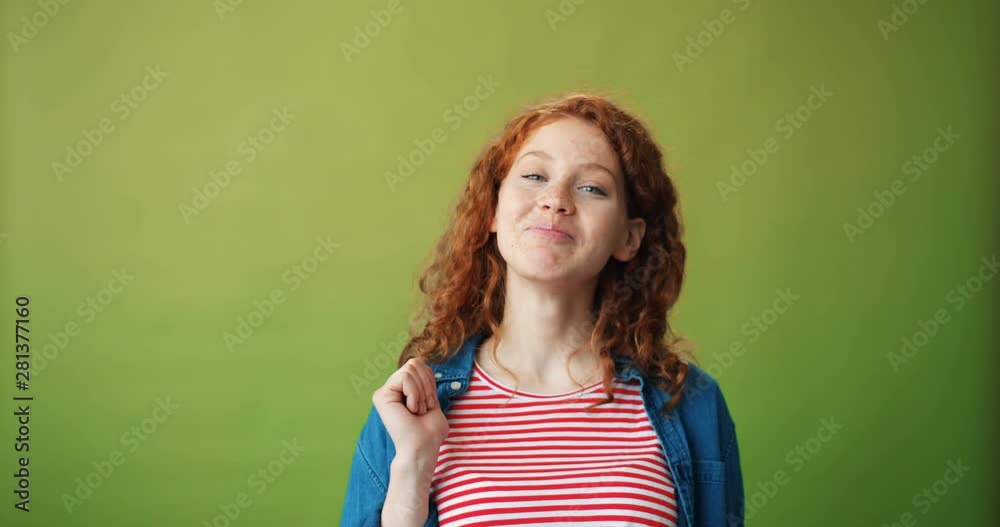Portrait of beautiful teenage girl sending air kiss and winking standing alone on green background smiling flirting. People, emotions and body language concept. Portrait of beautiful teenage girl sending air kiss and winking standing alone on green background smiling flirting. People, emotions and body language concept.