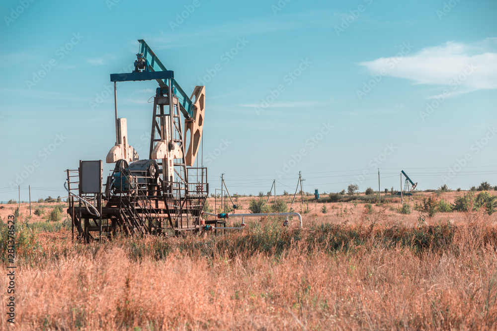 Fototapeta premium Oil well site pump jack and fields at in rural