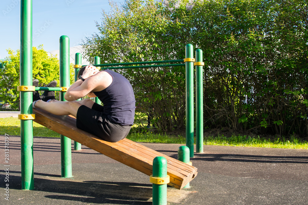 Fototapeta premium a man goes in for sports outdoors, on a special platform, does an exercise on a press