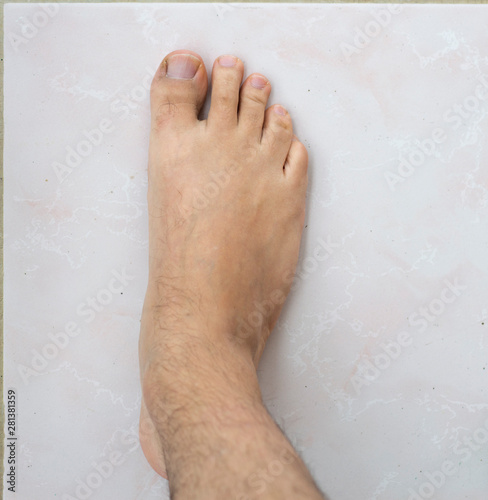 Selective focus. Male feet on faience floor (tile)