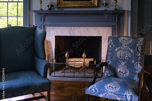 Retro blue armchairs near vintage fireplace with  fire wood. Vintage design mantelpiece. 