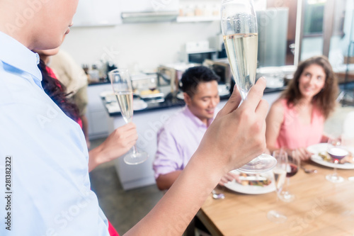 Man raising champagne flute toast with friends