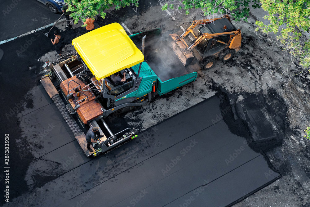 asphalt paver and loader are working to repair road. Laying new asphalt, top view. Workers manage paver and repair road surface. asphalt paver and loader are working to repair road. Laying new asphalt, top view. Workers manage paver and repair road surface.