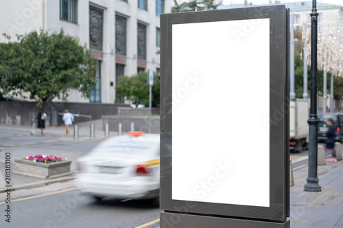 Mock up rectangular vertical lightbox onstreet in city. Advertising construction. Copy space. banner on sidewalk narrow street. Against backdrop building and passing car. © Денис Бухлаев