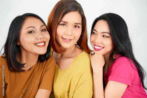 Portrait of three Asian girlfriends embracing each other smiling and posing at camera