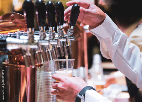 Bartender pouring draft beer in the bar  Barman hand at beer tap pouring draught lager beer serving in a restaurant or pub