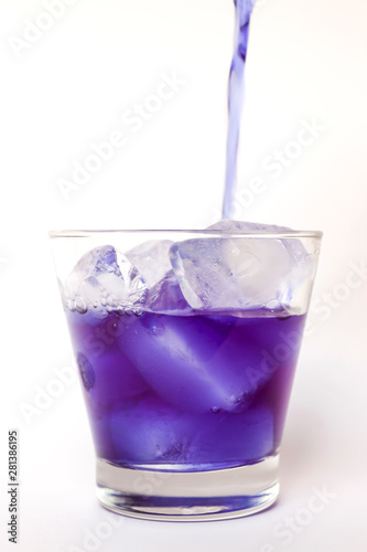 Pouring butterfly pea juice on ice in transparent glass isolated on white background 