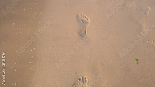 Walking woman on the sea beach, footsteps
