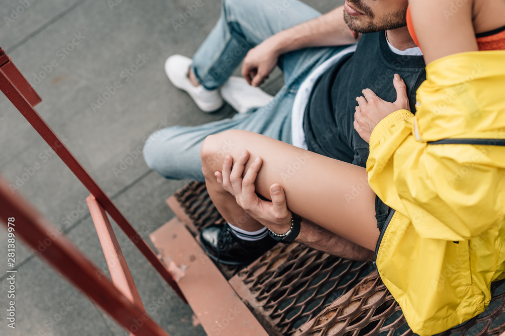 cropped view of woman and man hugging and sitting on stairs cropped view of woman and man hugging and sitting on stairs