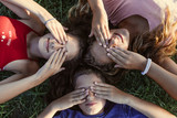 teenagers on the grass covering their eyes