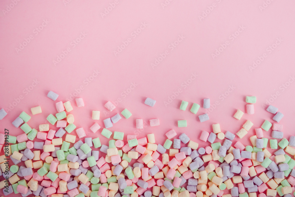 Marshmallows on pink background with copyspace. top view. Background or texture of colorful mini marshmallows