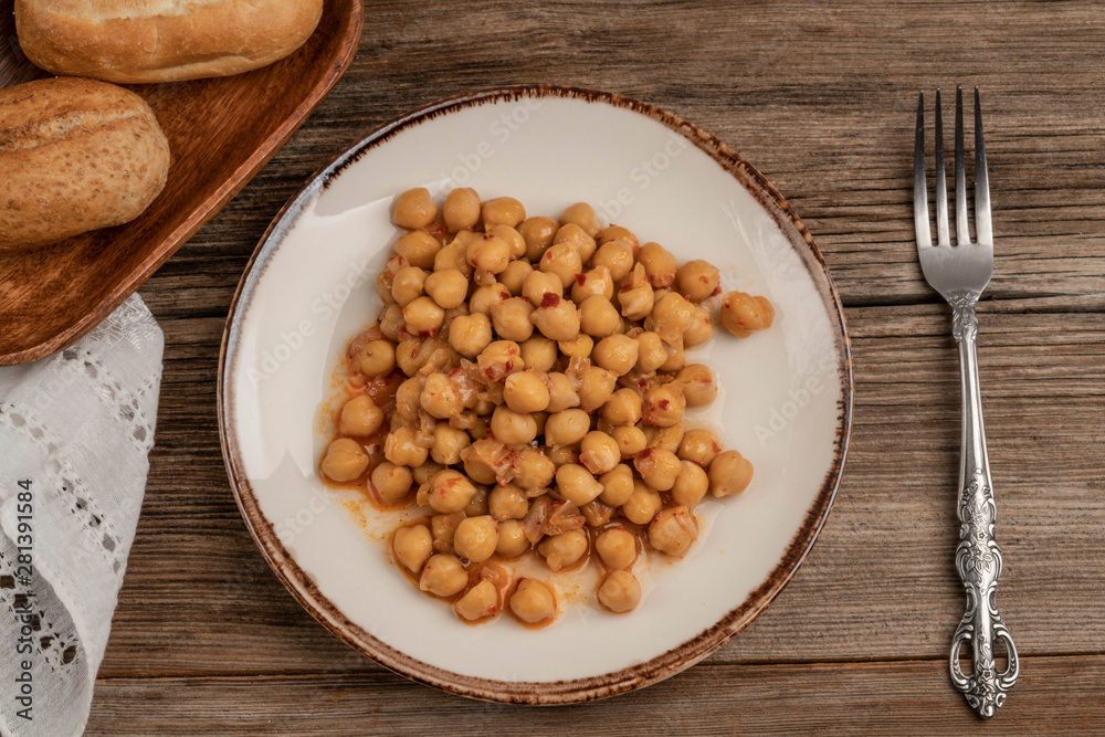 a plate of chickpea and bread on a wooden table a plate of chickpea and bread on a wooden table