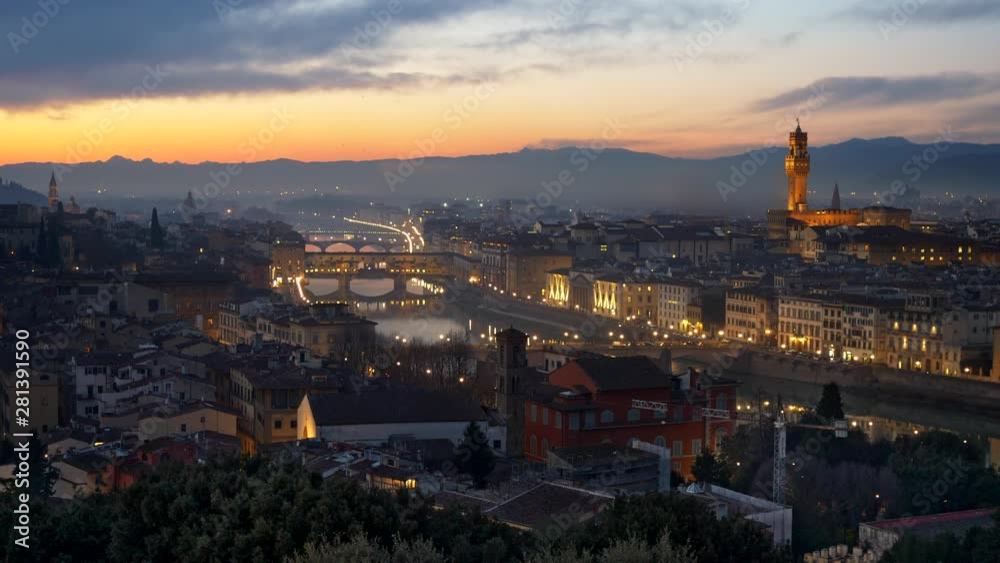 Dusk in Florence, Italy. Tower of Arnolfo, that is a part of Palazzo Vecchio, is seen on the right, the Ponte Vecchio Bridge over Arno River is seen in the center of this shot. Orange and blue sky Dusk in Florence, Italy. Tower of Arnolfo, that is a part of Palazzo Vecchio, is seen on the right, the Ponte Vecchio Bridge over Arno River is seen in the center of this shot. Orange and blue sky
