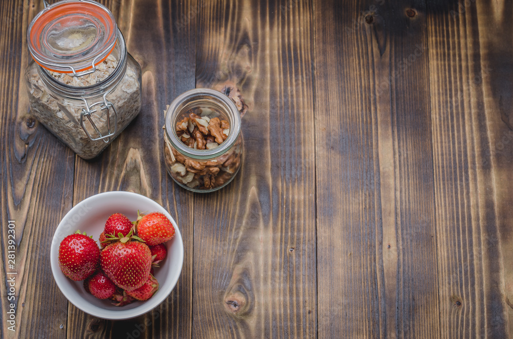 fresh strawberry, homemade granola and walnut in open glass jar on a wooden table. Copyspace and top view fresh strawberry, homemade granola and walnut in open glass jar on a wooden table. Copyspace and top view