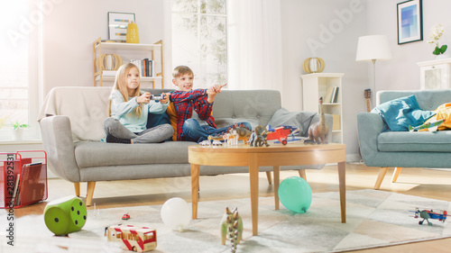 At Home: Cute Girl Playing in Video Game Console, Using Joystick Controller, Her Younger Brothe Cheers for Her. Happy Children Playing Videogames.