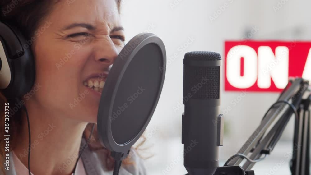 Close up of face of young Caucasian woman speaking very emotionally into mike in broadcast studio Close up of face of young Caucasian woman speaking very emotionally into mike in broadcast studio
