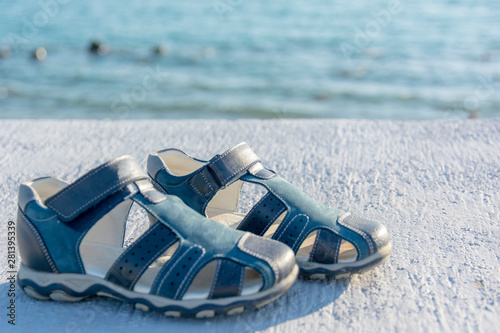 children's blue sandals on a bright sunny day against the blue sea