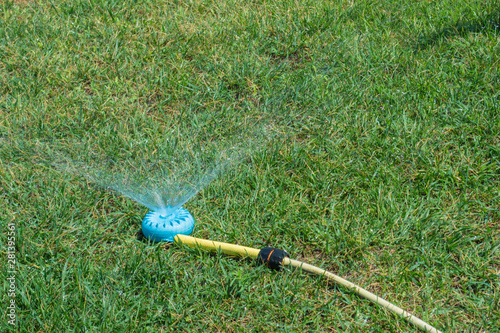 water spraying blue device. watering green grass