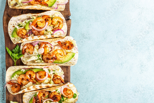 Shrimp tacos. Seafood fajitas with cabbage, onion, parsley in tortillas served on wooden cutting board. blank space for a text food background photo
