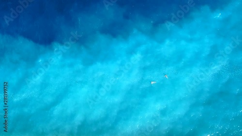 Aerial video from above of beautiful young couple swimming in the ocean at the tropical island beach.