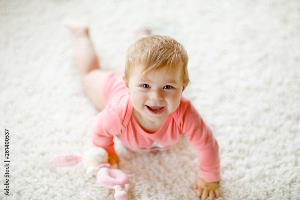 Little cute baby girl learning to crawl. Healthy child crawling in kids room with colorful toys. Back view of baby legs. Cute toddler discovering home and learning different skills Little cute baby girl learning to crawl. Healthy child crawling in kids room with colorful toys. Back view of baby legs. Cute toddler discovering home and learning different skills