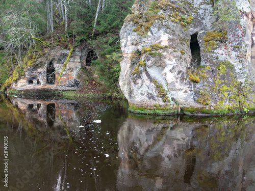 Sandstone rocks with caves reflect in dark water in Anfabrika, Ligatne, Latvia photo