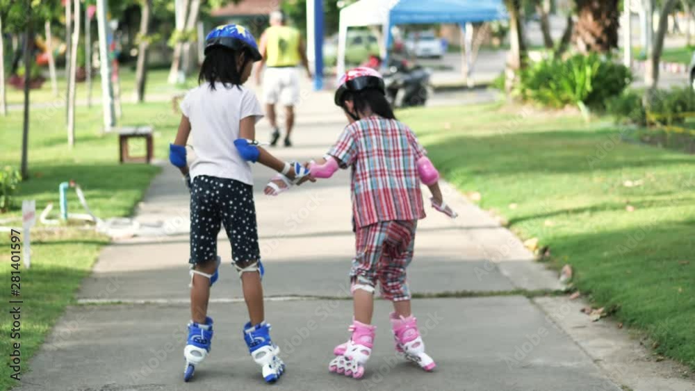 Happy Asian children playing roller skating together in the park outdoor, slow motion.