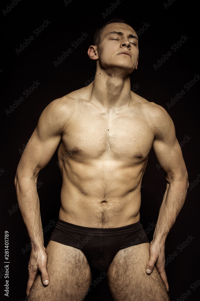 Fototapeta premium Strong stripped muscle male model in underwear on black isolated font background