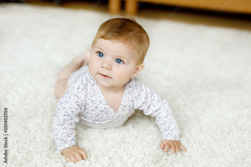 Little funny baby girl lifting body and learning to crawl.