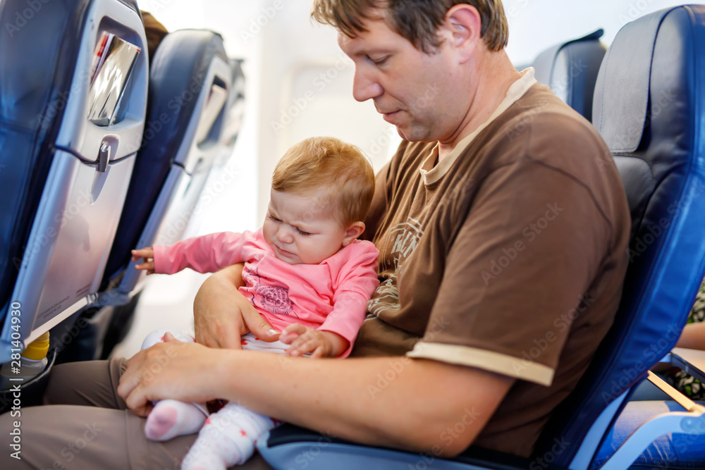 Young tired father and his crying baby daughter during flight on airplane going on vacations Young tired father and his crying baby daughter during flight on airplane going on vacations