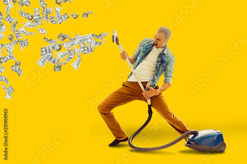 Young man having fun cleaning house with vacuum cleaner man collects money Vacuum photo