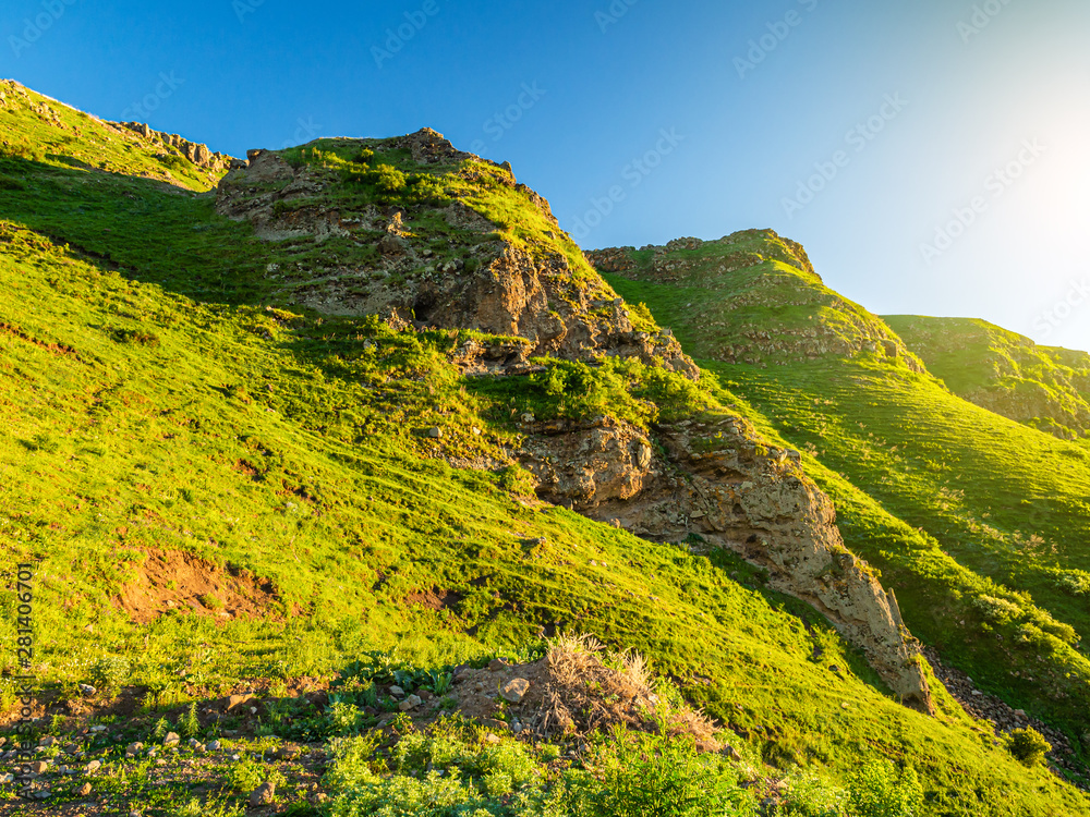 Rocky landscape with green hillsides illuminated by the evening sun