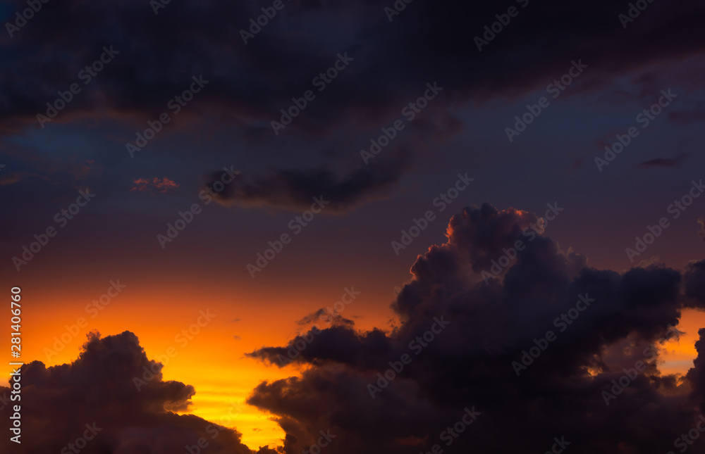 Dramatic view of cloudscape over background of colorful sunset sky, high contrast, low key.