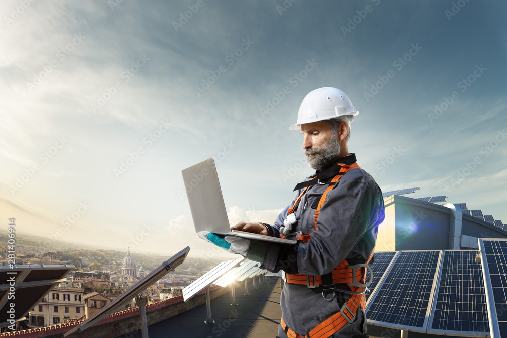Solar energy engineer using laptop for check station in roof Solar energy engineer using laptop for check station in roof