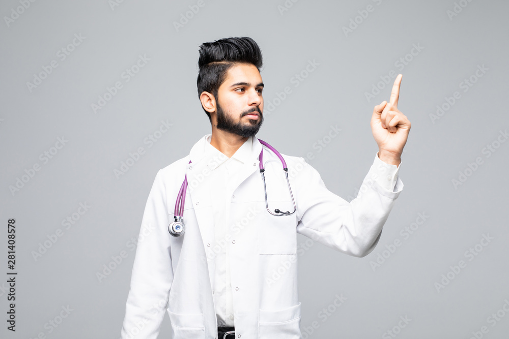 A portrait of a happy male doctor pointing at a copy space isolated on white background