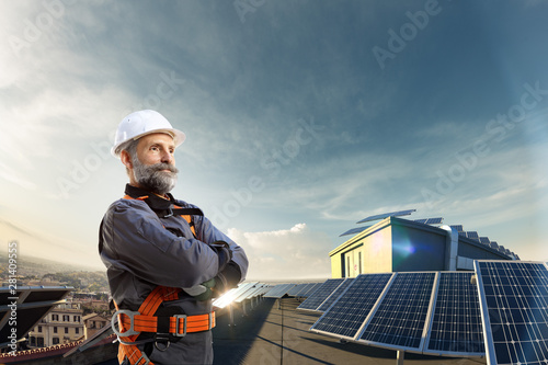 Happy engineer feel success after good work. He standing near solar station and looking beautiful sunset landscape
