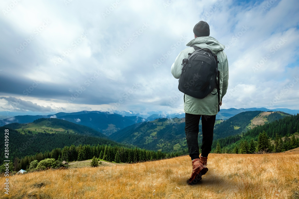 Creative background, A man is giant, a man is a tourist, he walks through a mountainous area with a backpack. The concept of Guliver, active tourism, recreation, the Carpathians. Mixed media