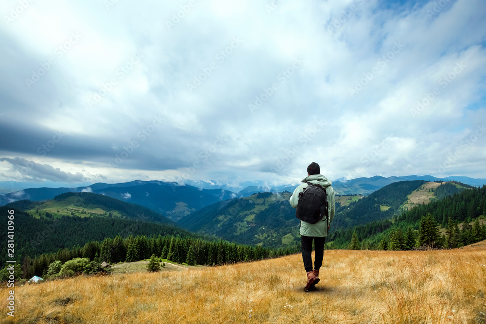 Creative background, A male tourist walks through a mountainous area with a backpack. The concept of active tourism, recreation, the Carpathians. Copy space