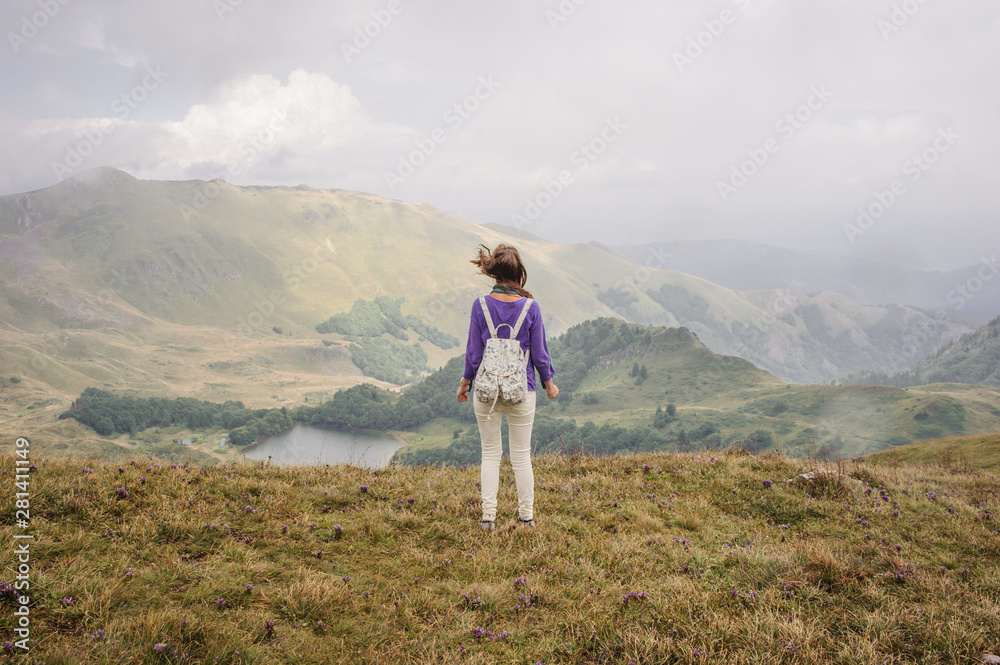 tourist girl looking at the mountains of montenegro in cloudy foggy weather, back
