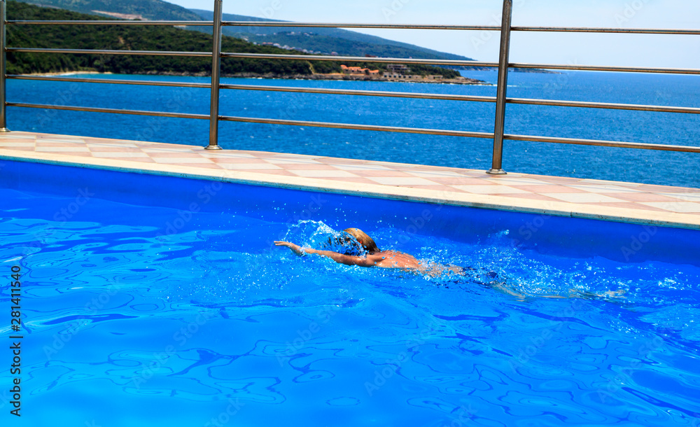 Obraz premium boy swims in pool on top of rocky seashore