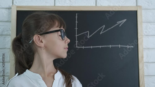 A graph on a blackboard. A smart schoolgirl with glasses with a growing graph drawn on the school board. photo