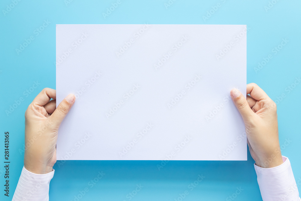 close up hands holding empty white blank letter paper size A4 for flyer or invitation mock up isolated on a blue background. close up hands holding empty white blank letter paper size A4 for flyer or invitation mock up isolated on a blue background.