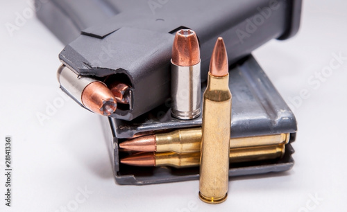 Two loaded magazines, one for a 9mm pistol and the other for a 223 caliber rifle on a white background photo