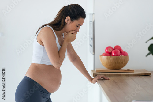 Slika na platnu Disgusted pregnant young woman suffering with nausea in morning at home