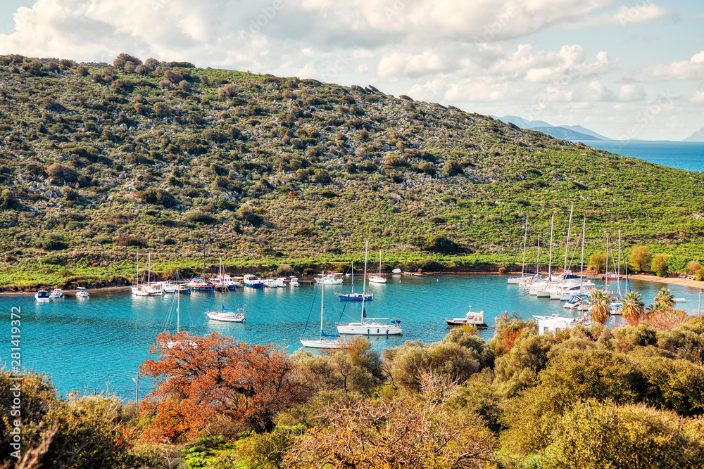 Yachts and boats anchored over the calm turquoise sea at gumsuluk bay in Bodrum, Mugla, Turkey.