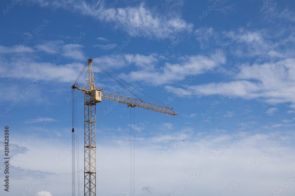 Industrial construction building crane against blue cloudy sky