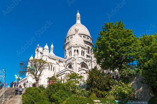Great side view of the famous monument Sacré-Coeur Basilica at the staircase between Rue du Cardinal Dubois and Rue Lamarck on a nice sunny day with a blue sky in Montmartre, Paris, France.  © H-AB Photography