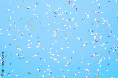 Multicolored confetti scattered on blue paper.Flat lay