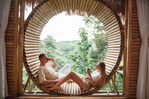 Romantic couple relaxes on a old wooden bungalow veranda, drinks coffee and enjoying life