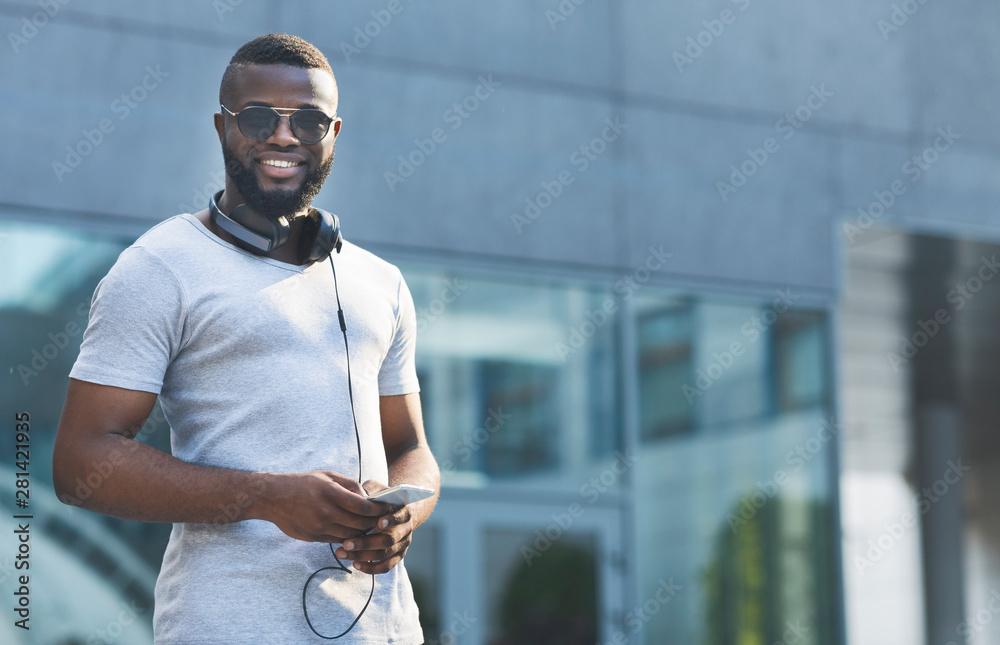 Handsome african man in sun glasses using cellphone in urban